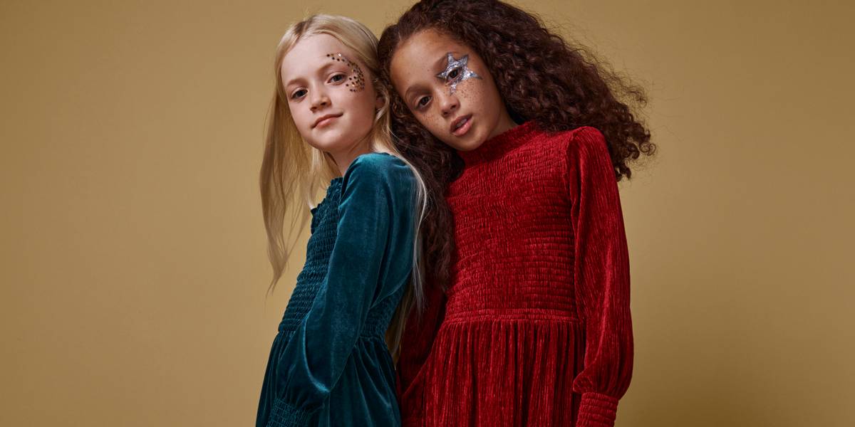 Two girls wearing velour party dresses. Shop partywear